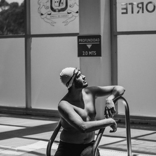 A focused man resting between strength training sets, looking determined and calm.